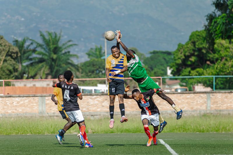 Footballers contesting an aerial ball, with the surrounding players visible