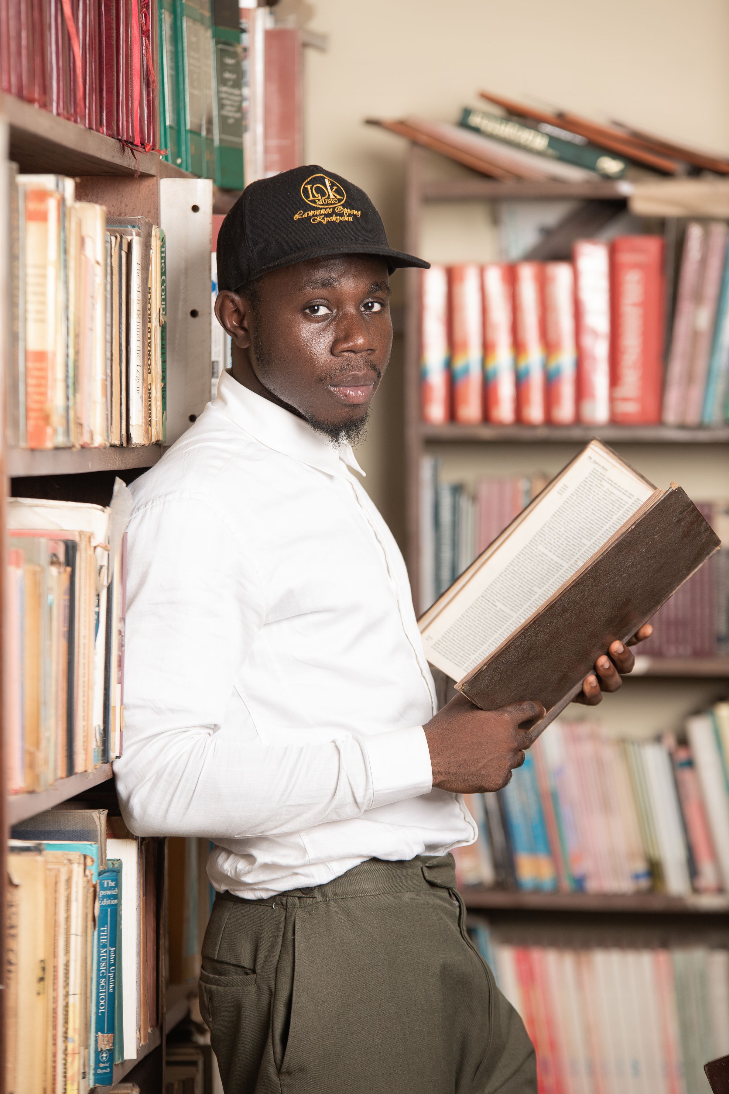 A young man holds an open book in a Ghanaian library
